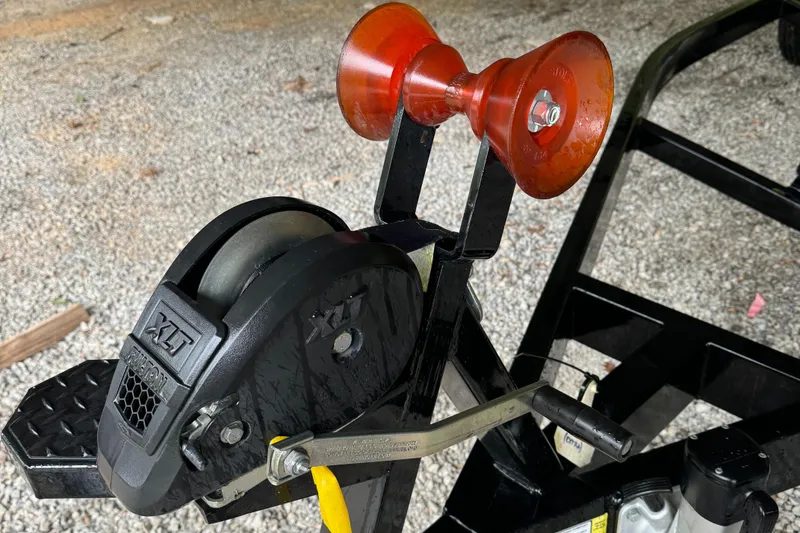 Slide: The Image of 2022 MasterCraft XT23 trailer winch and roller on gravel surface. - 7