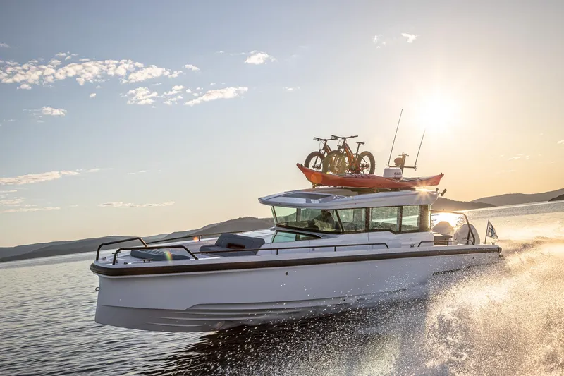 The Image of 2024 Axopar 37 XC Cross Cabin cruising at sunset with bikes and kayak on roof. - 0