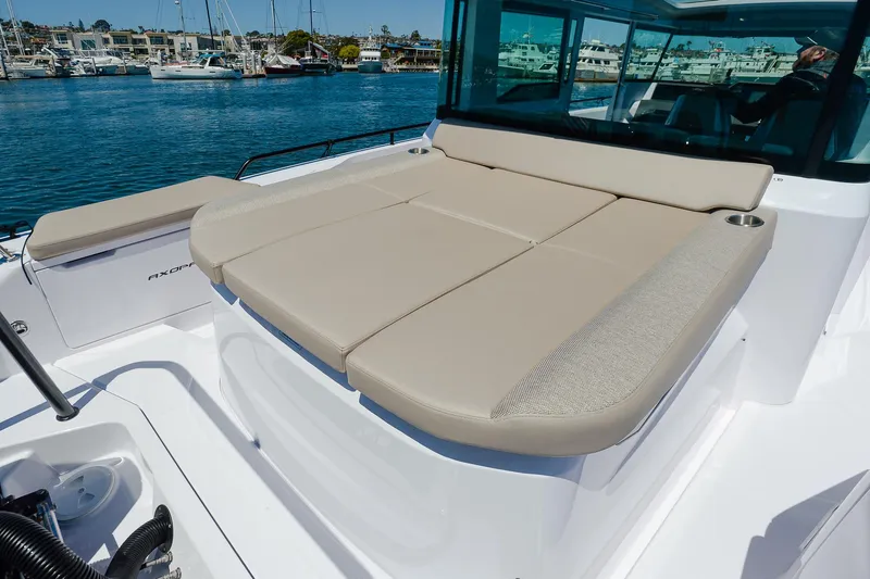 Slide: The Image of 2024 Axopar 37 XC Cross Cabin Aft Cabin with beige seating, docked in a marina. - 5