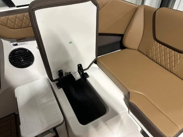 Slide: The Image of 2025 Yamaha Boats 222SD interior seating with storage compartment, tan upholstery, and speaker. - 15