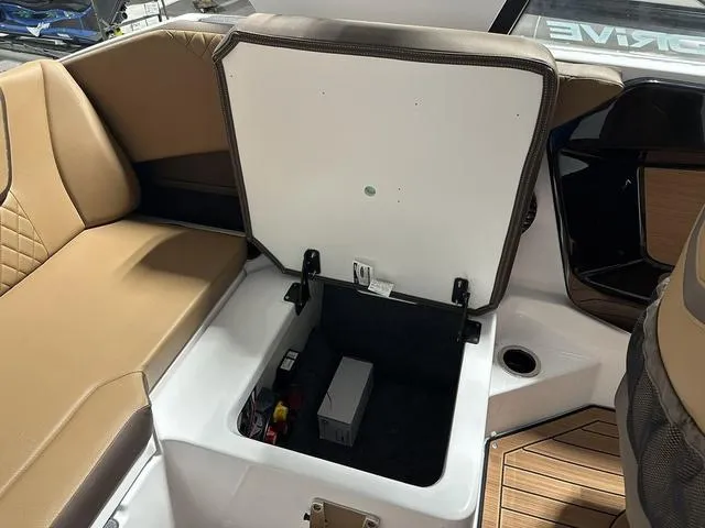 Slide: The Image of 2025 Yamaha Boats 222SD storage compartment with tan seating and open hatch. - 16