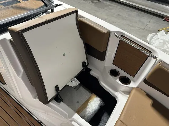 Slide: The Image of 2025 Yamaha Boats 222SD interior storage compartment with brown seating and cup holders. - 22