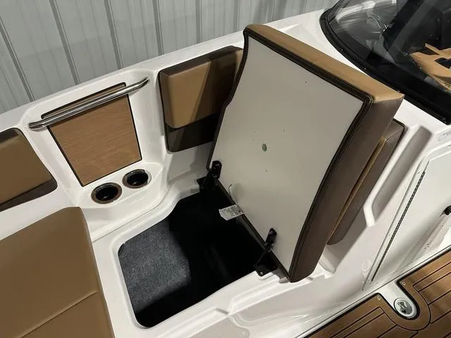 Slide: The Image of 2025 Yamaha Boats 222SD interior storage compartment with brown seating and cup holders. - 23