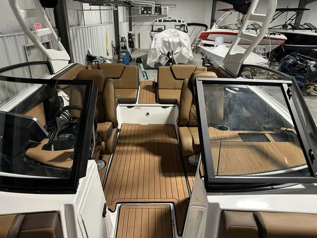 Slide: The Image of 2025 Yamaha Boats 222SD interior with brown seating and wood flooring in a showroom. - 25