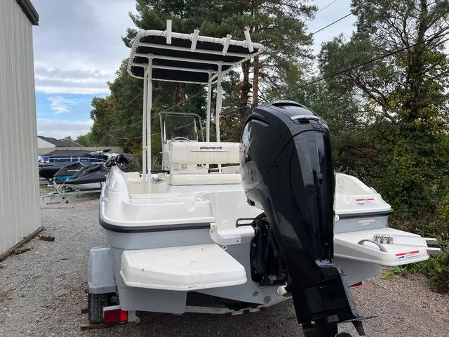 Slide: The Image of 2021 Bayliner T18BAY boat with outboard motor, parked outdoors near trees. - 4