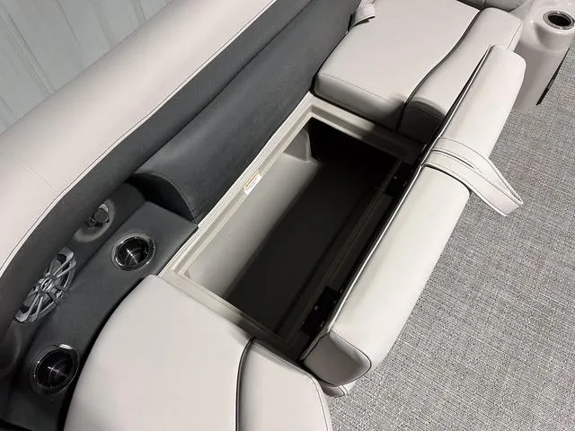 Slide: The Image of 2025 Barletta Aria A24QC boat interior with open storage compartment and cup holders. - 24