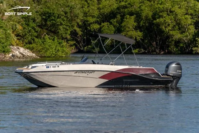 Slide: The Image of 2023 Starcraft SVX 231 OB DH boat on a calm river, surrounded by lush greenery. - 3