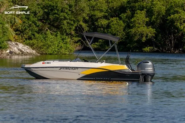 Slide: The Image of 2022 Starcraft SVX 191 OB boat on calm water with lush green background. - 2