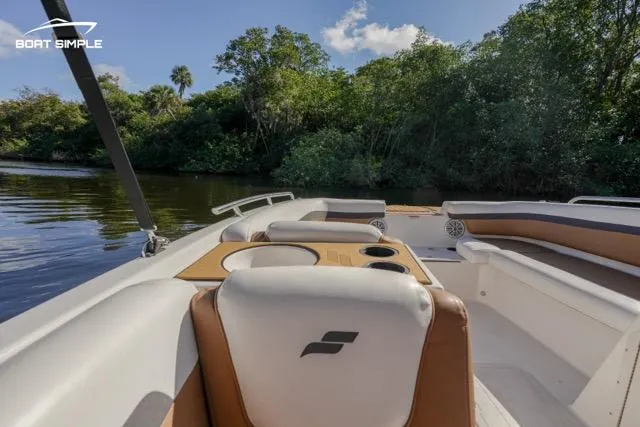 Slide: The Image of 2022 Starcraft SVX 191 OB boat interior with seating and cup holders, near lush greenery. - 6