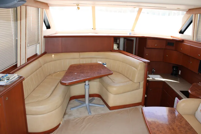 Slide: The Image of Interior of 2006 Silverton 42 Convertible yacht with beige seating and wooden table. - 13