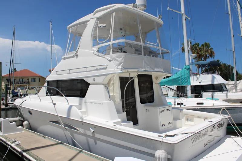 Slide: The Image of 2006 Silverton 42 Convertible yacht docked at a marina under clear blue skies. - 3