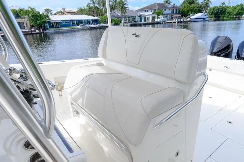 Slide: The Image of 2021 SeaVee 370z boat interior with white seating, docked by waterfront homes. - 11