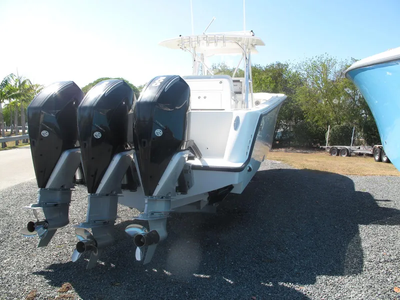 Slide: The Image of 2021 SeaVee 370z boat with triple outboard engines, parked on gravel. - 17
