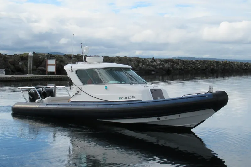Slide: The Image of 2007 Protector Targa 28 boat docked in calm waters, with rocky shoreline background. - 9