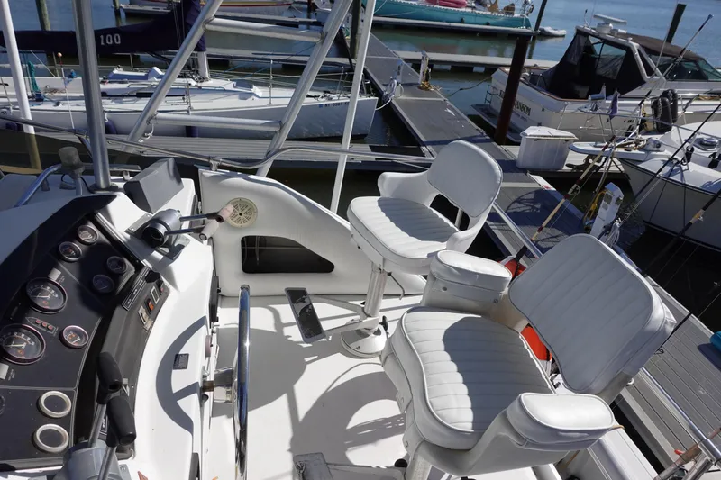 Slide: The Image of 1988 Trojan 10.8 Meter Sedan boat cockpit with white seating and control panel at marina. - 11