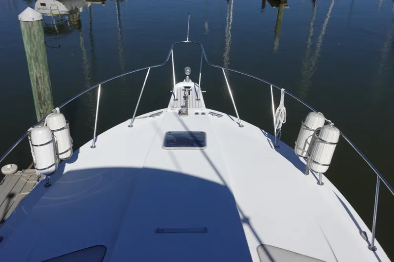 Slide: The Image of 1988 Trojan 10.8 Meter Sedan boat deck with fenders, docked in calm water. - 7