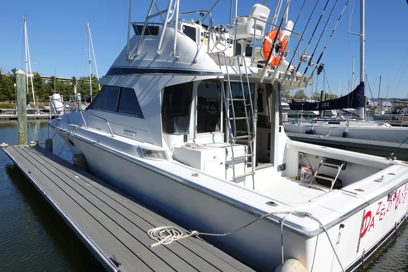 The Image of 1988 Trojan 10.8 Meter Sedan boat docked at a marina, featuring a spacious deck. - 1