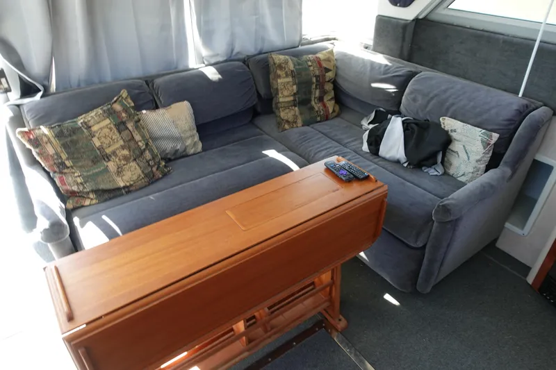 Slide: The Image of 1988 Trojan 10.8 Meter Sedan interior with gray sofa, wooden table, and decorative pillows. - 22