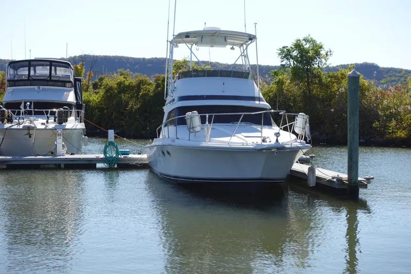 Slide: The Image of 1988 Trojan 10.8 Meter Sedan boat docked in a serene marina setting. - 4