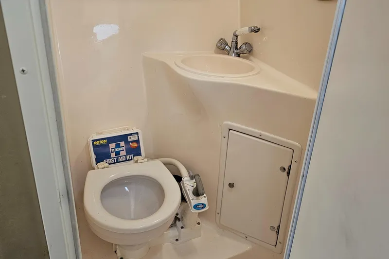 Slide: The Image of 2004 Rinker Fiesta Vee 250 boat bathroom with toilet, sink, and storage compartment. - 13