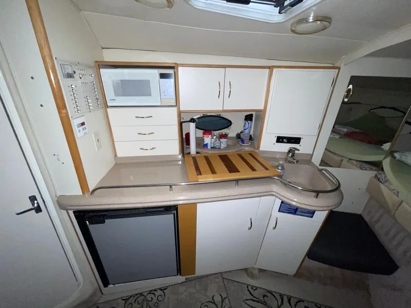 Slide: The Image of 1999 Larson 330 CABRIO boat kitchen with microwave, fridge, and sink. - 23