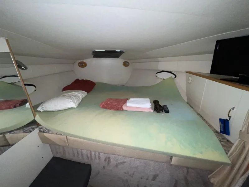Slide: The Image of 1999 Larson 330 CABRIO cabin interior with bed, pillows, and TV. - 28