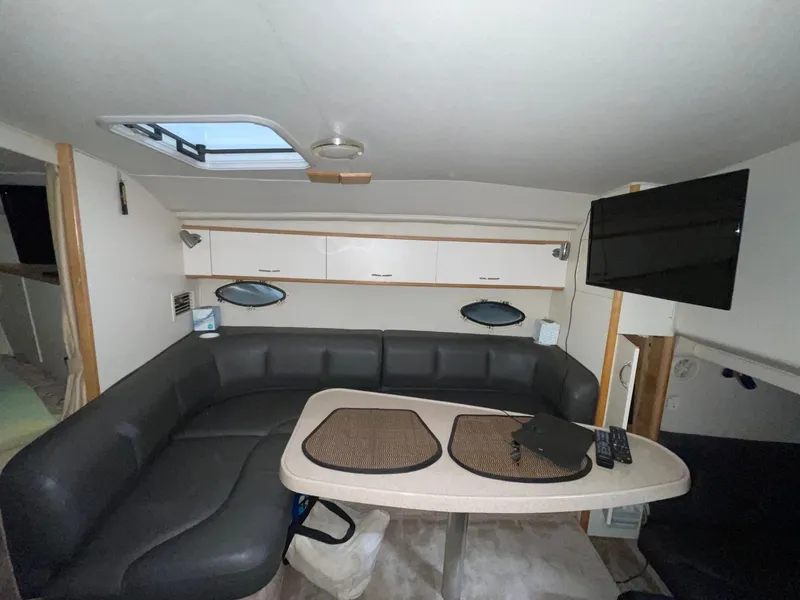 Slide: The Image of Interior of 1999 Larson 330 Cabrio boat with seating, table, and TV. - 29