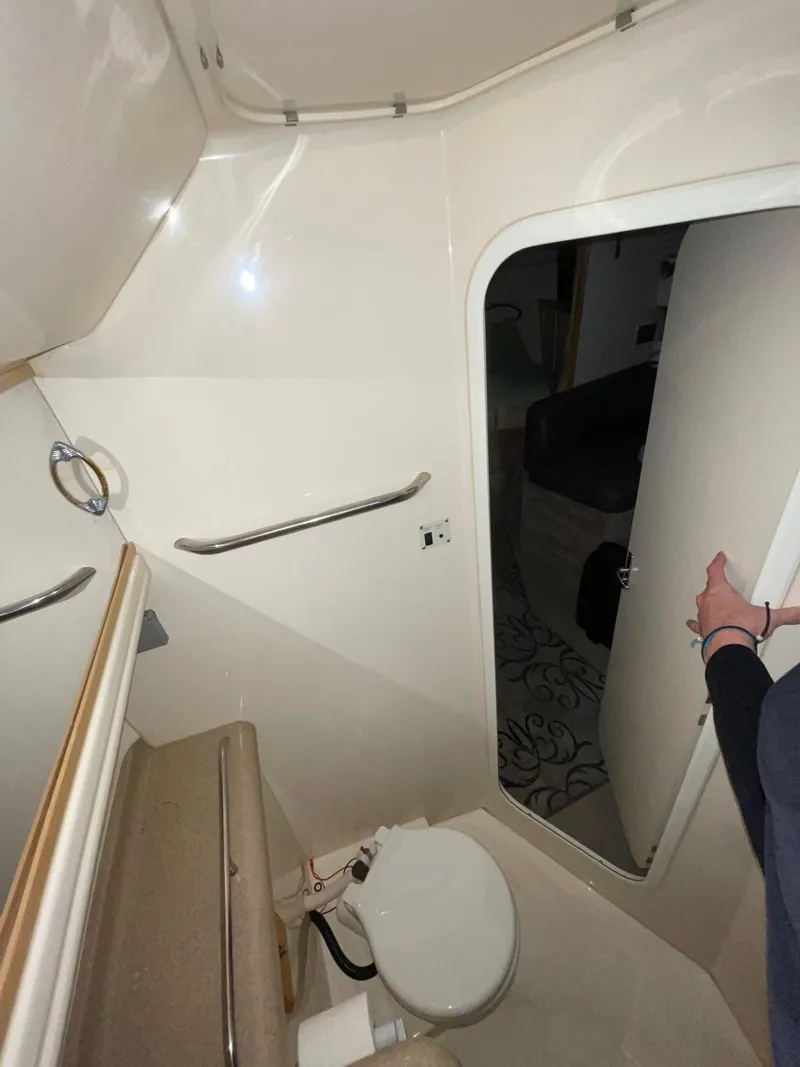 Slide: The Image of 1999 Larson 330 CABRIO boat bathroom interior with toilet and open door. - 33