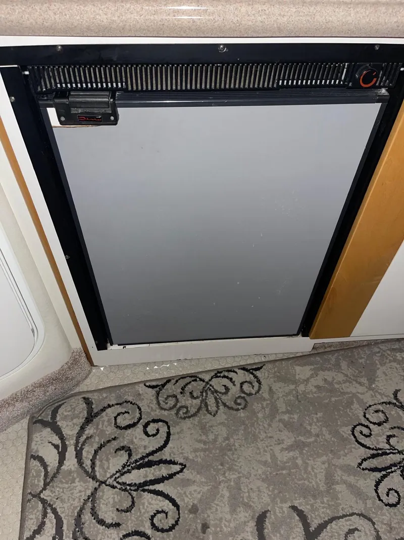 Slide: The Image of 1999 Larson 330 CABRIO interior with compact refrigerator and decorative carpet. - 34