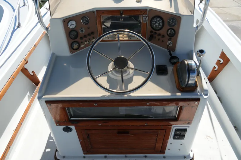 Slide: The Image of 1980 Mako 23 inboard boat dashboard with steering wheel and gauges. - 13