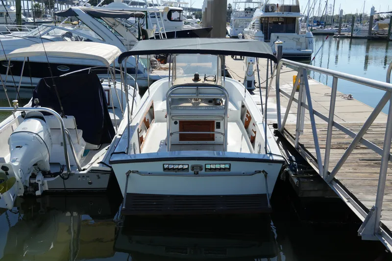Slide: The Image of 1980 Mako 23 inboard boat docked at a marina, surrounded by other vessels. - 3