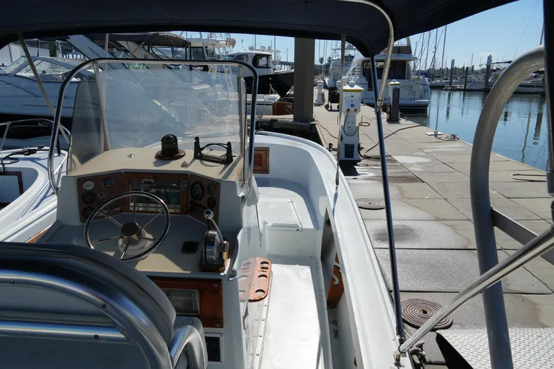 Slide: The Image of 1980 Mako 23 inboard boat docked at marina, featuring steering console and seating area. - 7