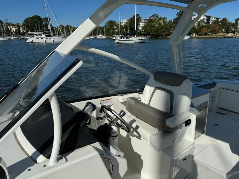 Slide: The Image of 2020 World Cat 280 DC x boat interior with steering wheel and seating, docked on a sunny day. - 16