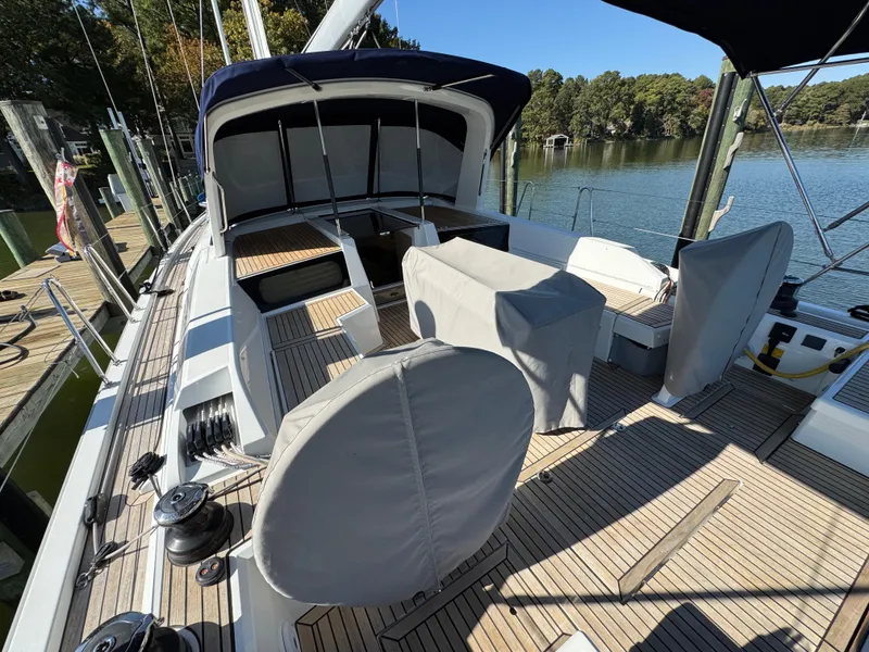 Slide: The Image of 2022 Beneteau Oceanis 46.1 sailboat deck with covered seating, docked by a serene lake. - 19