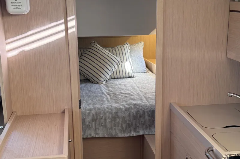Slide: The Image of Cozy cabin interior of 2022 Beneteau Oceanis 46.1 with striped bedding and wooden finish. - 23