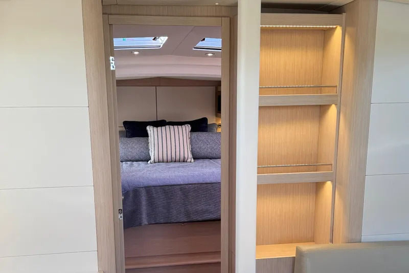 Slide: The Image of Interior of 2022 Beneteau Oceanis 46.1 yacht, featuring cozy bedroom and elegant wooden shelving. - 32