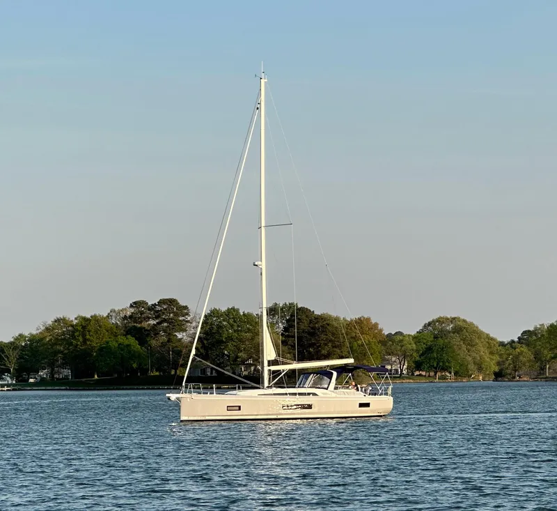 Slide: The Image of 2022 Beneteau Oceanis 46.1 sailboat on calm water with trees in background. - 38