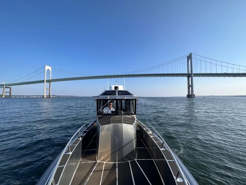 Slide: The Image of 2023 Life Proof 31 Walk Around Cabin boat cruising under a large suspension bridge. - 3