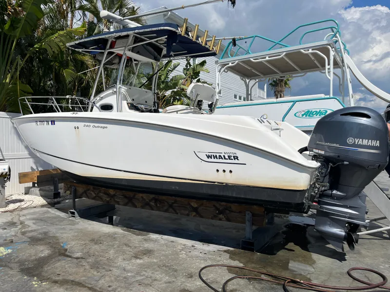 Slide: The Image of 2004 Boston Whaler 240 Outrage boat with Yamaha engine, docked outdoors. - 0