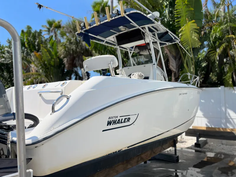 Slide: The Image of 2004 Boston Whaler 240 Outrage boat on display, surrounded by lush greenery. - 23