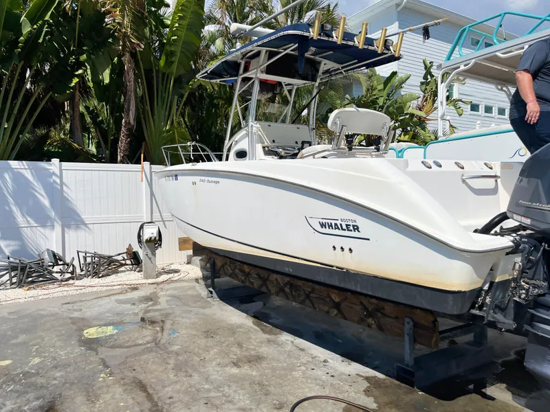 Slide: The Image of 2004 Boston Whaler 240 Outrage boat on a lift, surrounded by tropical foliage. - 29