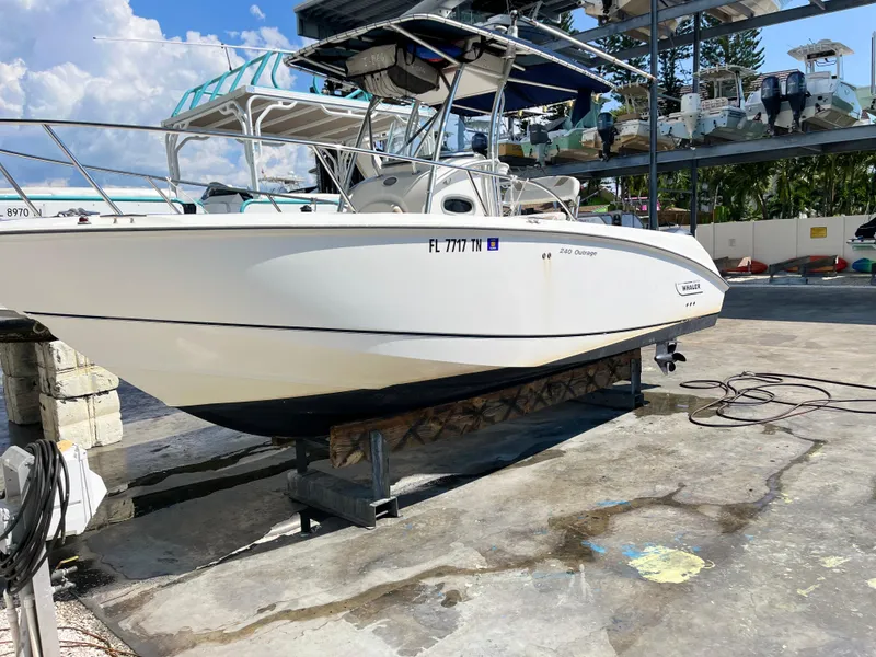 Slide: The Image of 2004 Boston Whaler 240 Outrage boat on dry dock, sunny day, marina background. - 39
