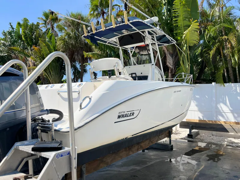 Slide: The Image of 2004 Boston Whaler 240 Outrage boat on trailer, surrounded by tropical foliage. - 6