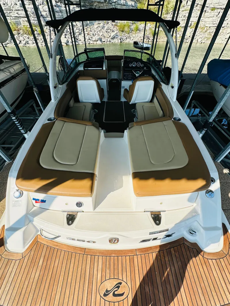 Slide: The Image of 2015 Sea Ray 250 SLX boat with tan seating and sleek design in a marina. - 25