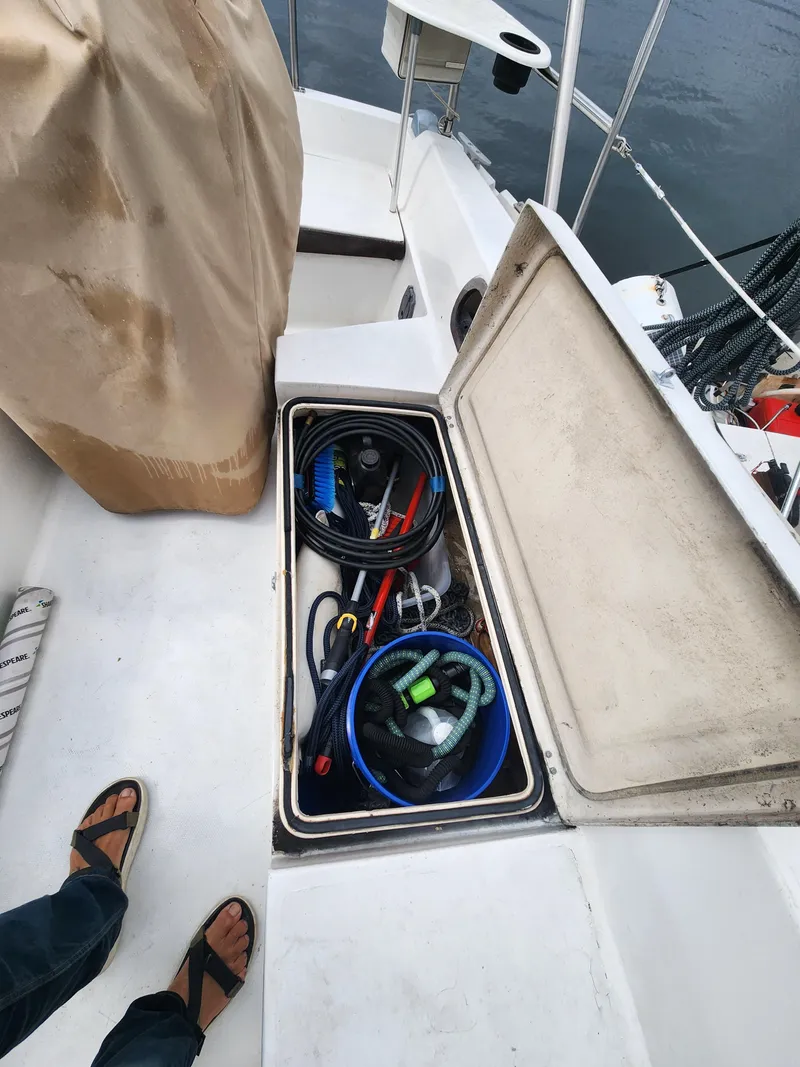 Slide: The Image of Open storage compartment on 1987 Catalina 36 sailboat deck, containing various boating equipment. - 13