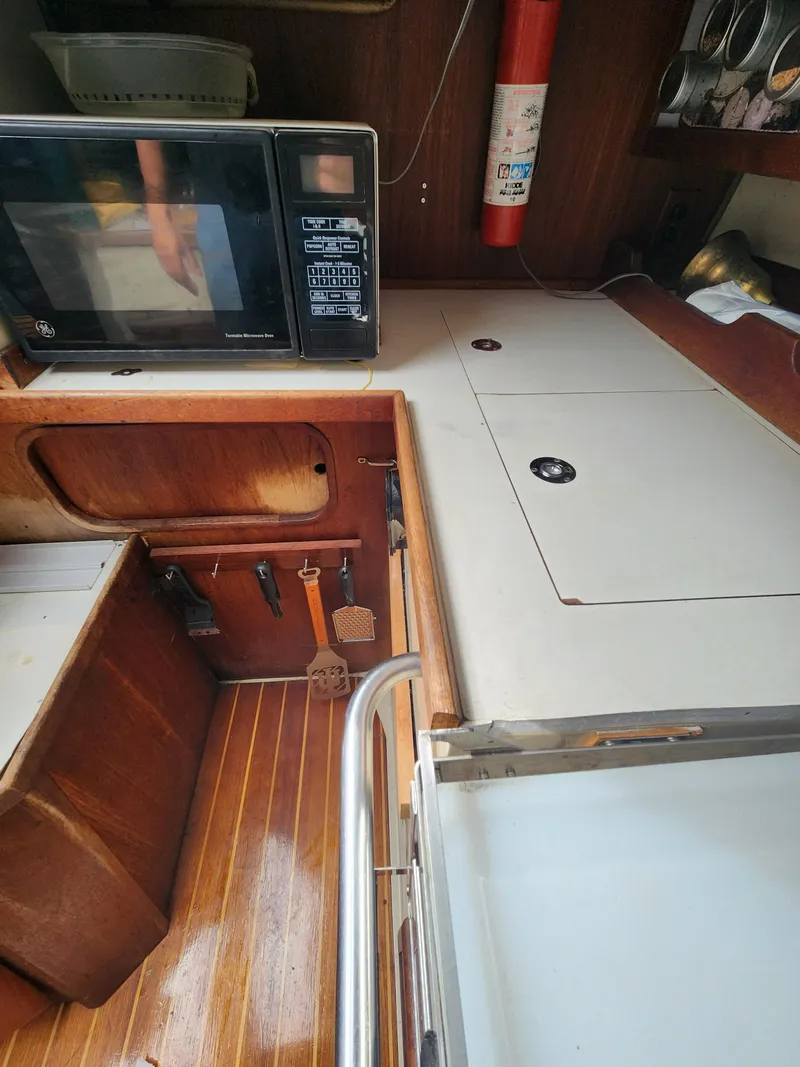 Slide: The Image of Galley of 1987 Catalina 36 sailboat with microwave and wooden cabinetry. - 19
