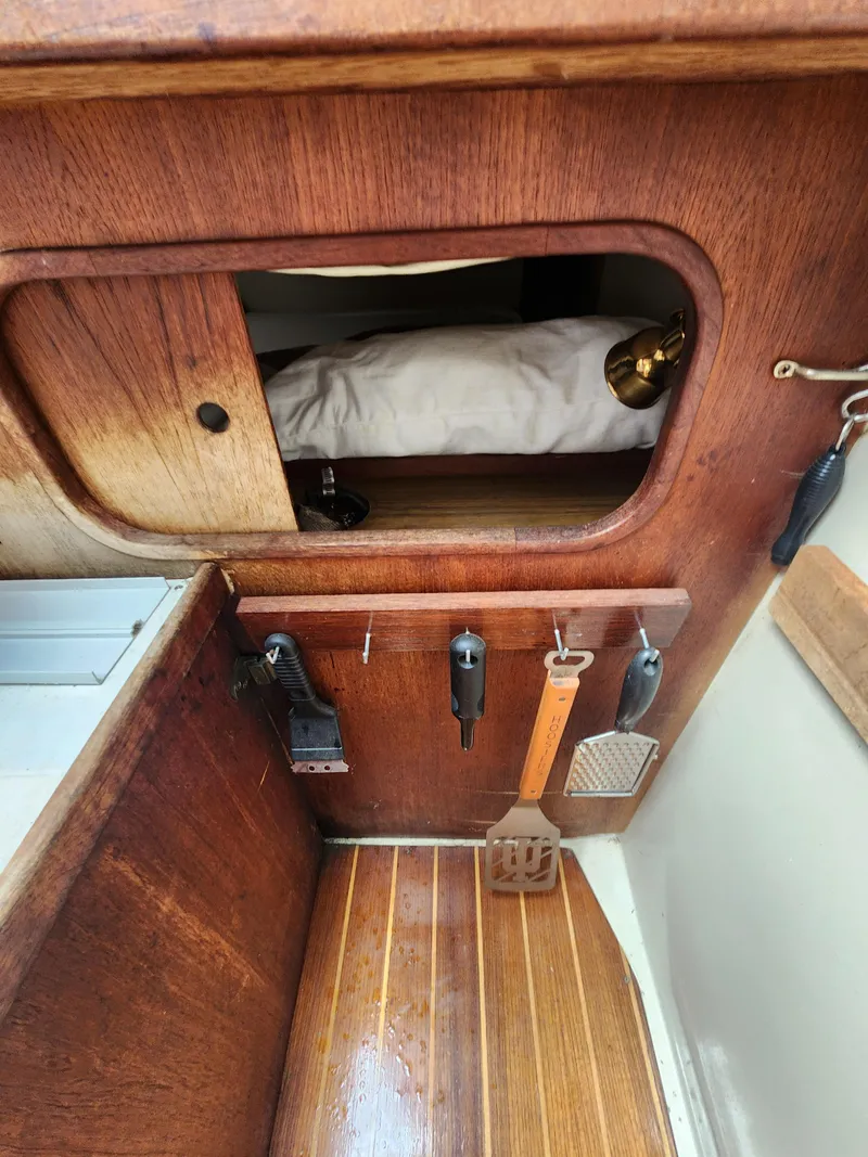 Slide: The Image of Wooden interior of a 1987 Catalina 36 sailboat with tools and a small storage area. - 20