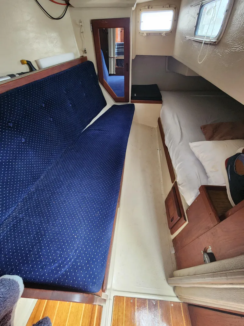 Slide: The Image of Interior of 1987 Catalina 36 sailboat with blue cushioned seating and cozy sleeping area. - 21