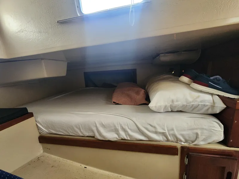 Slide: The Image of Cozy cabin bed inside a 1987 Catalina 36 sailboat, with pillows and shoes. - 22