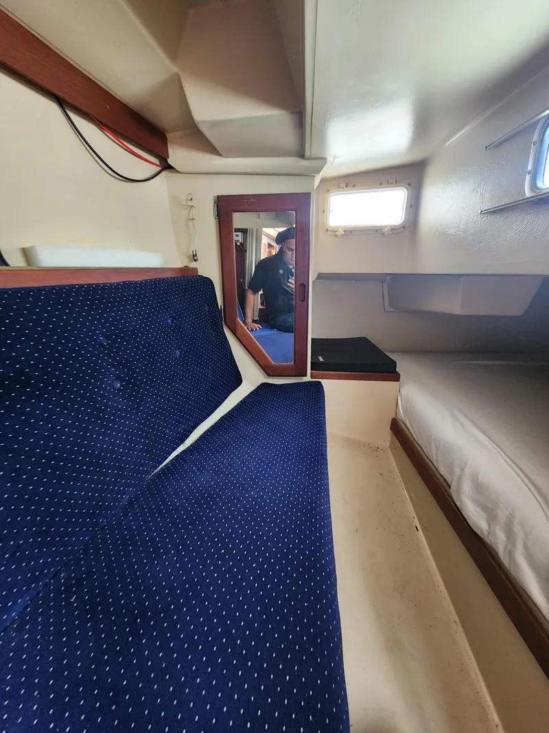 Slide: The Image of Interior of 1987 Catalina 36 sailboat with blue seating and small window. - 23